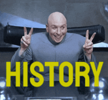 a bald man is giving a peace sign in front of a sign that says history
