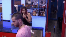 a man in a pink shirt is standing in front of a woman in a black tank top