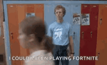 a man in a blue shirt is standing in front of a row of lockers in a locker room .