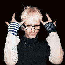 a man wearing glasses and striped gloves is making a devil horns sign