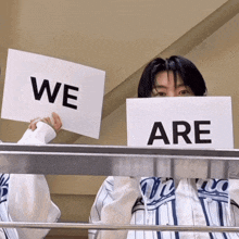 a person holding up a sign that says " we are "