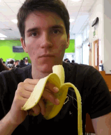 a young man in a black shirt is peeling a banana