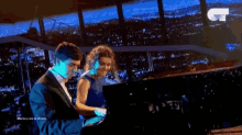 a man and a woman are playing piano in front of a city skyline