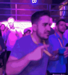 a man in a blue shirt is dancing in front of a sign that says ' b ' on it