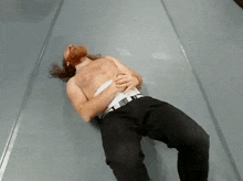 a shirtless man is laying on the floor with his hands on his stomach