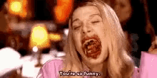 a woman in a pink shirt is eating something and says `` you 're so funny . ''