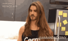 a man with long hair and a beard is standing in front of a refrigerator ..