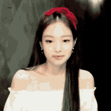 a close up of a woman wearing a red headband and earrings .