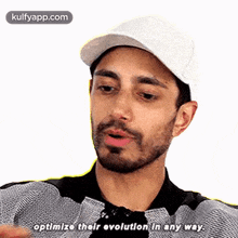 a man with a beard is wearing a white hat and a black shirt and is talking .