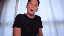 a young boy in a black t-shirt is making a funny face .