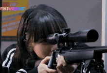 a girl is holding a sniper rifle in front of an eniverse sign