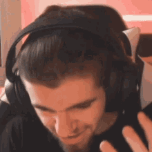 a man wearing headphones is sitting in a gaming chair and smiling .