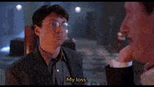 a man in a suit and tie is talking to another man and says my loss