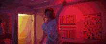 a girl is dancing in a room with pink lights and paintings .