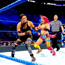 two women are fighting in a wrestling ring with a referee watching .