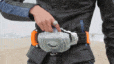 a person wearing a black leather jacket and an orange belt with a ring on their finger