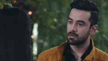 a man in a yellow jacket is looking at a woman in a black shirt