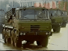 a row of military trucks are driving down a road