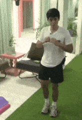 a man in a white shirt and black shorts is standing on a green carpet