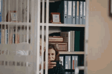 a woman is taking a picture of a man behind a fence in a library .