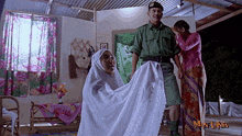 a man in a military uniform stands next to a woman in a hijab and a man in a green uniform