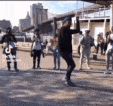 a group of people are dancing on a sidewalk with a tiktok logo on the bottom right