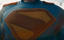 a man in a blue superhero suit is standing in front of a city