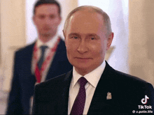 a man in a suit and tie stands in front of another man
