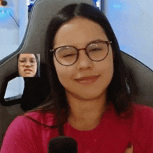 a woman wearing glasses is sitting in a chair and smiling .