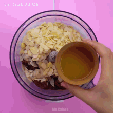a person pours orange juice into a food processor filled with almonds