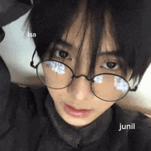 a close up of a person wearing glasses with the name junil on the bottom right corner