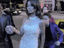a woman in a white dress holds hands with a man in a blue suit