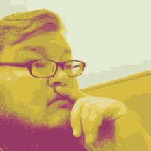 a man with glasses and a beard holds his finger to his mouth