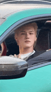 a man with blonde hair is sitting in a green sports car
