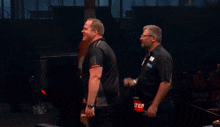 two men are standing in front of a bottle of beer