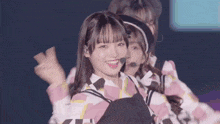 a girl in a pink and white striped shirt is smiling while dancing