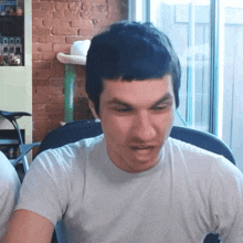 a man wearing a white t-shirt is making a funny face