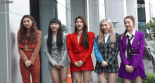 a group of girls standing in front of a building with honeycam on the bottom left