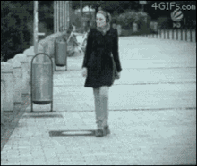 a woman walking down a sidewalk with a 4gifs.com logo on the bottom
