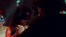 a man in a tuxedo is kissing a woman in a mask