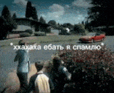 a red car is driving down a street with a group of people standing on the side of the road