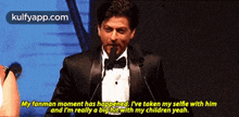 a man in a tuxedo is speaking into a microphone and says my fanman moment has happened