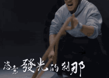 a man in a hoodie is holding a rope in front of chinese writing