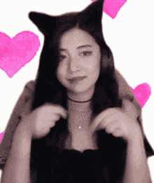 a woman wearing a cat ear headband with pink hearts behind her