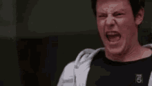 a man is making a funny face with his mouth open and his hands in the air .
