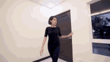 a woman in a black shirt is standing in a room next to a door
