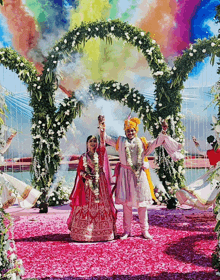 a bride and groom are standing in front of a floral archway