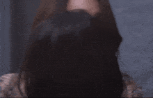 a woman with long hair is standing in front of a blue wall