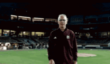 a man wearing a maroon jacket with the letter m on it