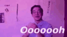 a man in a blue shirt is clapping his hands in front of a purple wall .